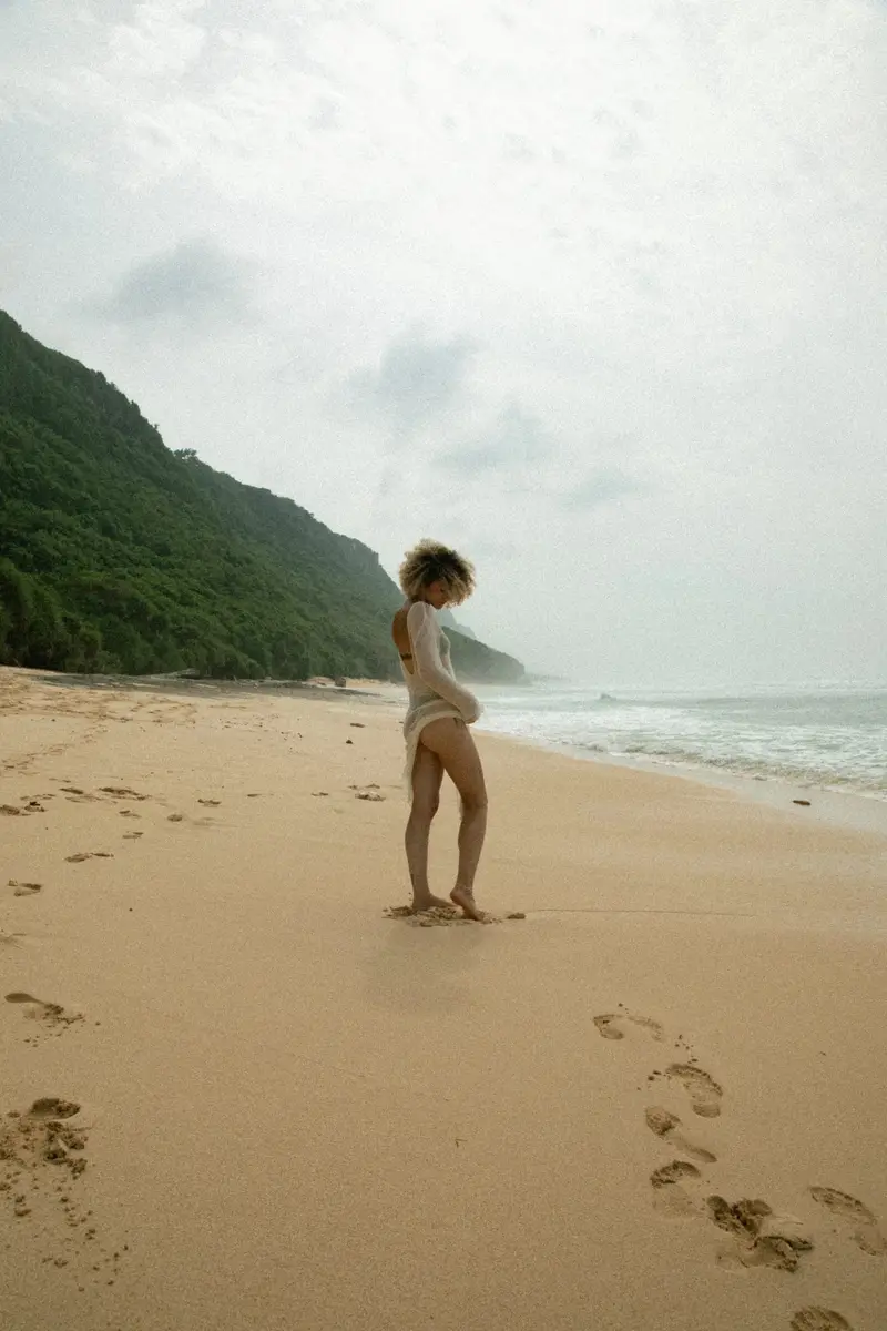 Silhouette seule sur une grande plage au pied d'une colline verdoyante