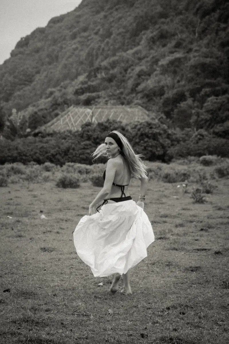 Femme en jupe blanche qui tourne dans un champ, en noir et blanc