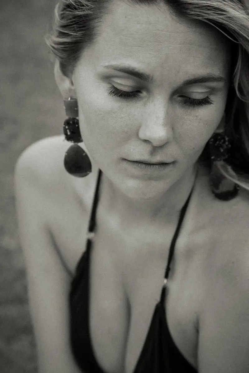 Portrait en noir et blanc d'une femme aux grandes boucles d'oreilles, le regard baissé