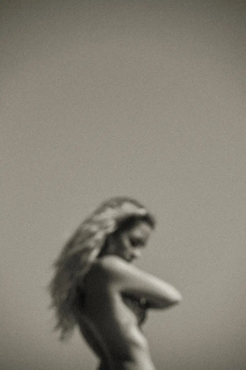 Silhouette floue d'une femme de profil sur fond gris, en noir et blanc