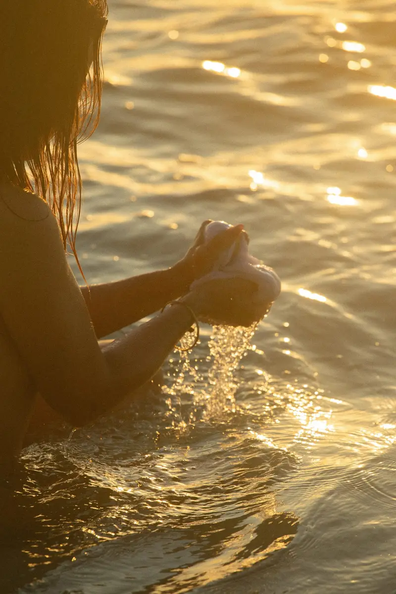Mains qui recueillent l'eau dorée au coucher du soleil