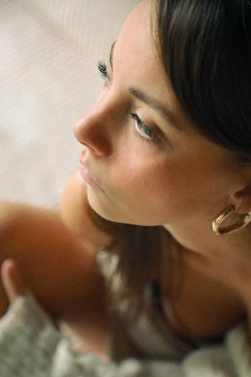 Portrait doux d'une femme aux créoles dorées, le regard au loin